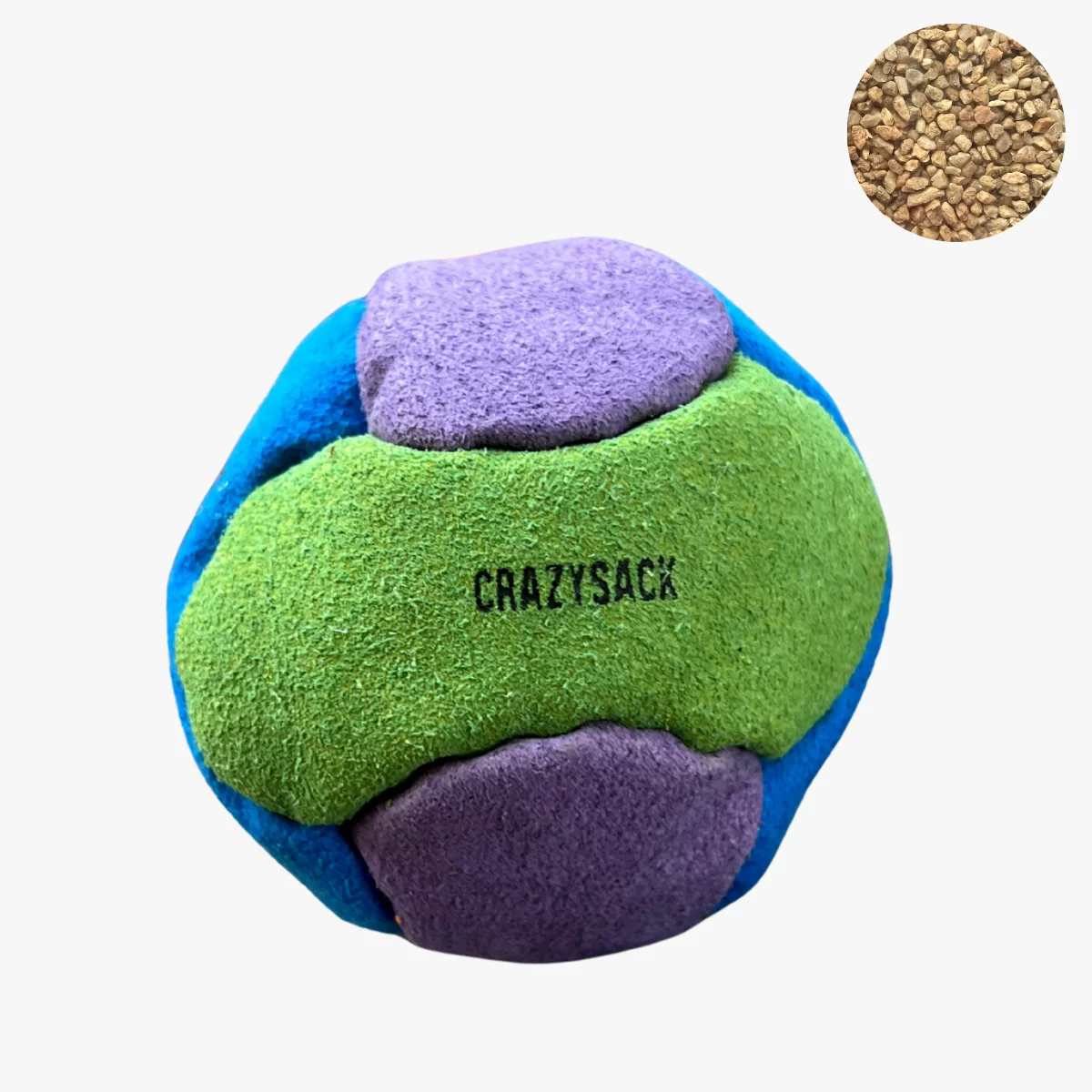 Ein grün lila hellblauer Footbag liegt auf einem grauen Kiesuntergrund