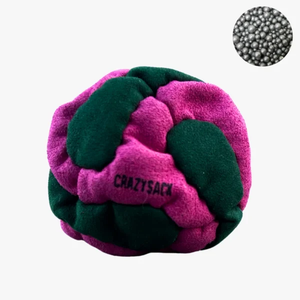 Ein pink grüner Footbag liegt draußen auf einem grauen Kiesweg