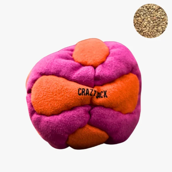 Ein pink orange Footbag liegt im Freien auf einem grauen Kiesweg